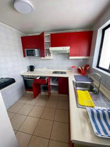 una pequeña cocina con armarios rojos y fregadero en Departamentos Heimat 2, en La Serena