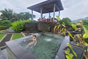 a boy swimming in a pool in a garden at Onion Garden And Natural Hotspring in Kubupenlokan