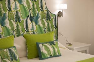 1 dormitorio con cama con almohadas verdes y papel pintado en Green Suite, en Sorrento