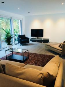 ein Wohnzimmer mit einem Sofa und einem Flachbild-TV in der Unterkunft Modernes Ferienhaus mit 2 Balkonen, Terrasse und Garten ! in Bochum