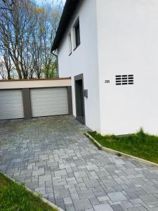 a white house with two garage doors and a driveway at Modernes Ferienhaus mit 2 Balkonen, Terrasse und Garten ! in Bochum