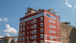 un edificio alto de color rojo con ventanas en la parte superior en Equine Hotel, en Ruiru