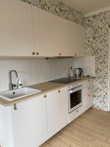 a kitchen with white cabinets and a sink at Familjehuset Sunnemo in Sunnemo