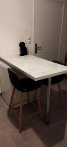 een wit bureau met 2 stoelen in een kamer bij Super studio, proche centre ville in Rochefort