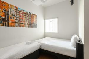 فندق إيزي أمستردام سيتي سنتر صاوث في أمستردام: سريرين في غرفة مع لوحة على الحائط