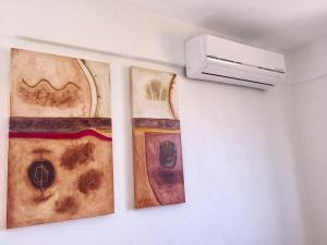 deux œuvres d'art sur un mur à côté d'un radiateur dans l'établissement Quinta Carrizalillo, à Puerto Escondido