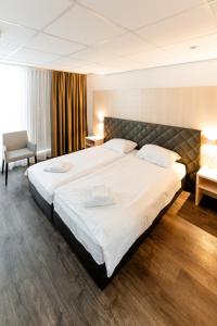 una habitación de hotel con una cama grande y una silla en Los Lorentes Aparthotel Bern Airport, en Belp