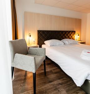 a hotel room with a bed and a chair at Los Lorentes Aparthotel Bern Airport in Belp