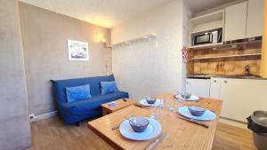 a living room with a table and a blue couch at St Christophe - 21B - Studio pied de piste - 4 per in Les Deux Alpes