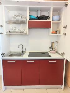 a kitchen with red cabinets and a sink at Rooms&Apartments Hotel Danci in Borghetto Santo Spirito