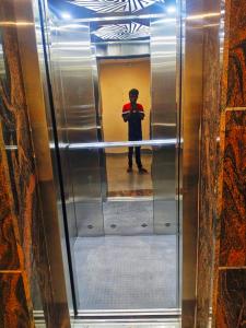 a man standing in a elevator in a mirror at MS Comforts Mahadevapura in Bangalore