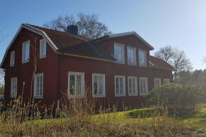 een rood huis met witte ramen op een veld bij Sörgården - hyr hela gården! (2-35 personer.) in Köping