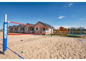 uma praia com uma rede de voleibol e um parque infantil em Morska Gąska- domki letniskowe em Mielenko