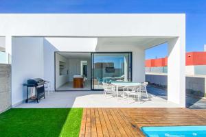 a house with a patio with a table and chairs at LEA LUXURY GOLF HOUSE in Caleta De Fuste