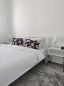 Cama blanca con 2 almohadas y mesa en Apartmani Iva en Banja Koviljača