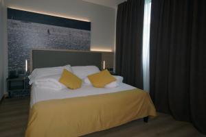 Ambassador Suite Hotel في ريفا ديل غاردا: غرفة نوم بسرير مع وسادتين صفراء