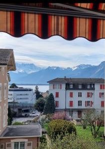 een raam met uitzicht op gebouwen en bergen bij Asima in Montreux
