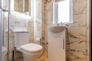 a bathroom with a toilet and a sink and a window at Stunning Central Derby Apartment Free WiFi & Parking in Derby