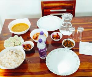a wooden table with white plates and bowls of food at JDreamland Homestay in Jorhāt