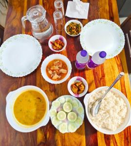 uma mesa de madeira coberta com tigelas de comida e sopa em JDreamland Homestay em Jorhāt