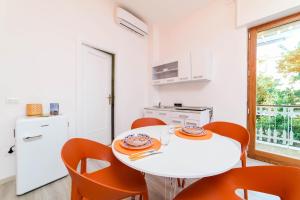 a white kitchen with a white table and orange chairs at Estate4home - Casa Laura in Sant'Agnello