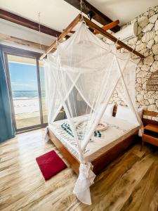 a bed in a room with a view of the beach at Just Heaven Apartments in Matemwe