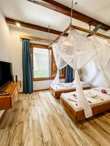 two beds in a room with wooden floors and a tv at Just Heaven Apartments in Matemwe