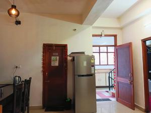 a kitchen with a refrigerator next to a door at The White House Shimla in Shimla