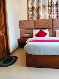 a bedroom with a large bed with red pillows at The White House Shimla in Shimla
