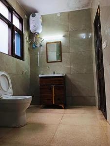 a bathroom with a toilet and a sink and a mirror at The White House Shimla in Shimla