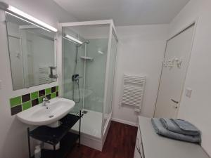 een witte badkamer met een douche en een wastafel bij Holiday flat near the beach on the Emerald Coast in Saint-Cast-le-Guildo