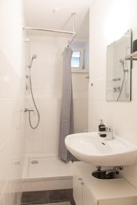 a white bathroom with a sink and a shower at Luxuswohnung mit Kinozimmer im Herzen Berlins BY HOMELY in Berlin