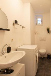 bagno bianco con lavandino e servizi igienici di Luxuswohnung mit Kinozimmer im Herzen Berlins BY HOMELY a Berlino