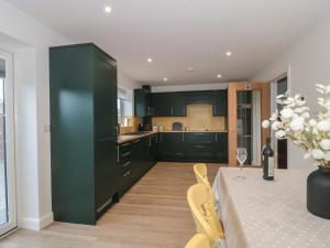 a kitchen with green cabinets and a table with chairs at The Stables in Highbridge
