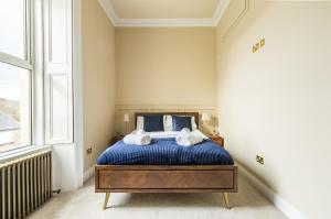 um quarto com uma cama com lençóis azuis e uma janela em Greystones Harbour Apartments em Na Clocha Liatha