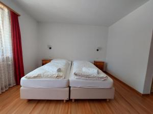 um sofá branco num quarto com uma cortina vermelha em B&B Alpenrösli em Gasenried