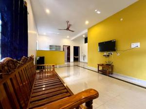 sala de estar con sofá y TV en una pared amarilla en Sea View JC Villa, en Kottakupam