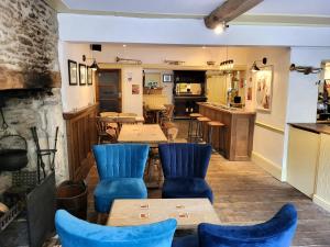 a restaurant with blue chairs and tables and a kitchen at Swan Inn Lechlade in Lechlade