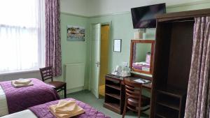 a bedroom with a bed and a desk with a mirror at Southcliff Guest House in Tenby