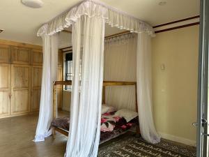 1 dormitorio con cama con dosel y cortinas blancas en Ridgeway Victoria, en Wakiso