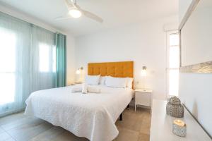 - une chambre blanche avec un grand lit et des draps blancs dans l'établissement Precioso chalet a pie de playa, à Punta Umbría