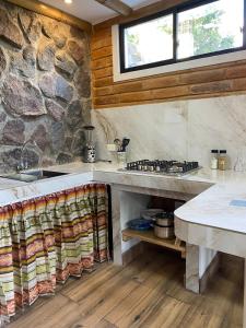 a kitchen with a stove and a stone wall at Watzara Wasi Cottage Familiar Camprestre Y Lofts en Cotacachi in Cotacachi