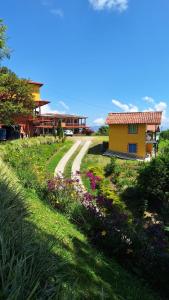 Alojamiento Campestre Cabañas Mirador Ingrumá Riosucio Caldas في Ruiosucio: بيت فيه طريق بجانب ميدان ورد