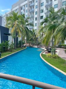 a large swimming pool with palm trees in front of a building at Arcadia Beach Resort Condominium in Pattaya South