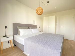 a bedroom with a large white bed and a lamp at Ferienwohnung Pier 21 Olpenitz in Olpenitz