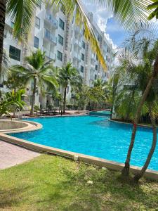 a swimming pool with palm trees in front of a building at Arcadia Beach Resort Condominium in Pattaya South