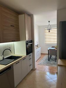 a kitchen with white cabinets and a sink and a table at Apartment GeoMo in Mostar