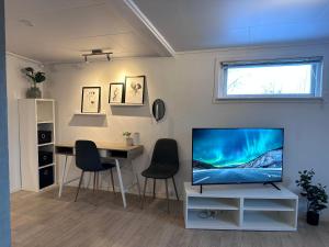 een woonkamer met een tv en een tafel met stoelen bij Fin sentral leilighet i Lakselv! in Lakselv