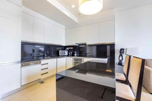a kitchen with white cabinets and black appliances at Daniels 1BR at Address Marina High Floor with Marina View in Dubai