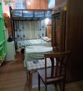 two beds in a room with a chair and a table at Paseo Verde Condominium in Manila